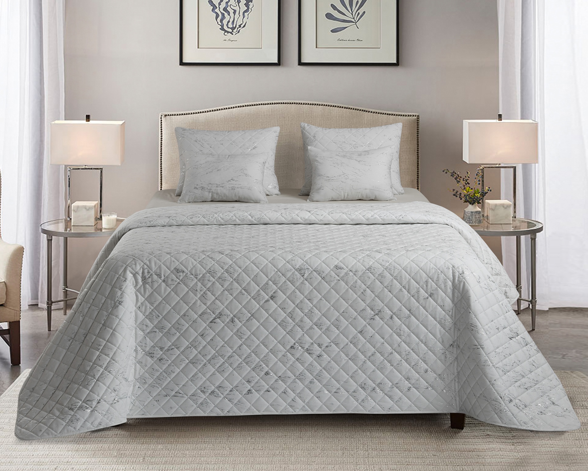 Cama casal com colcha e almofadas cinzentas e abajures em mesas laterais