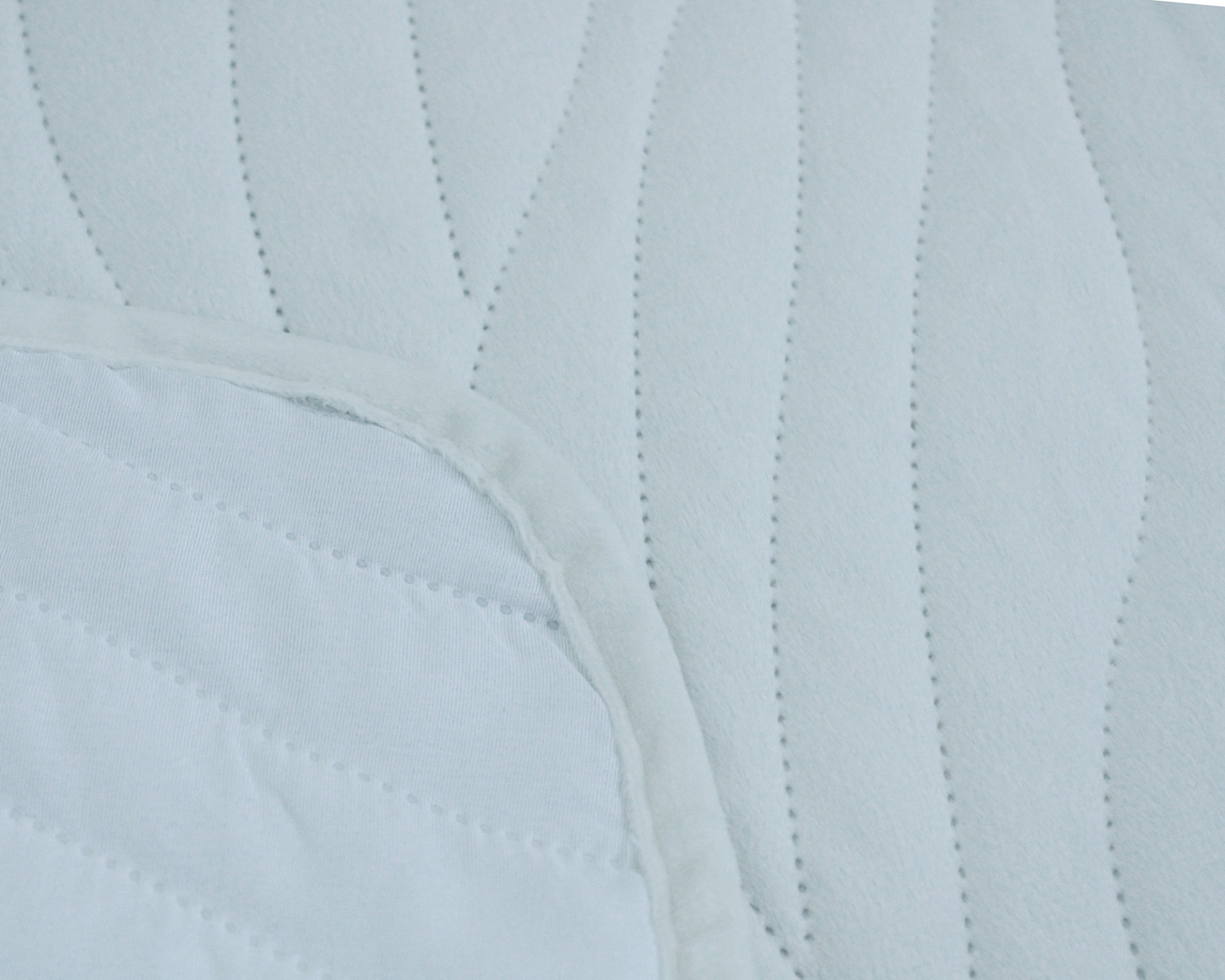 Tecido branco acolchoado com padrão ondulado em costura.