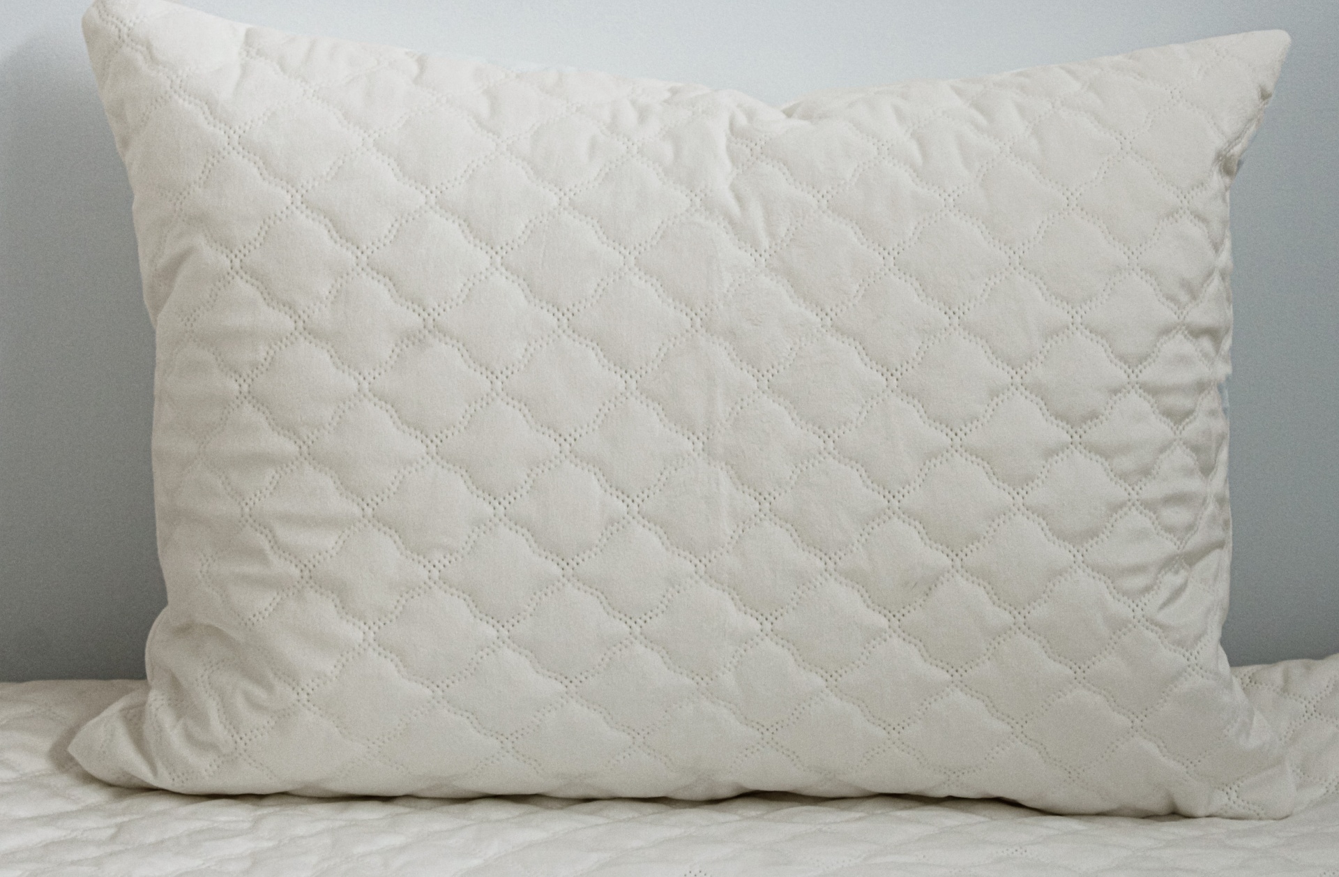 Travesseiro branco acolchoado com padrão de losangos