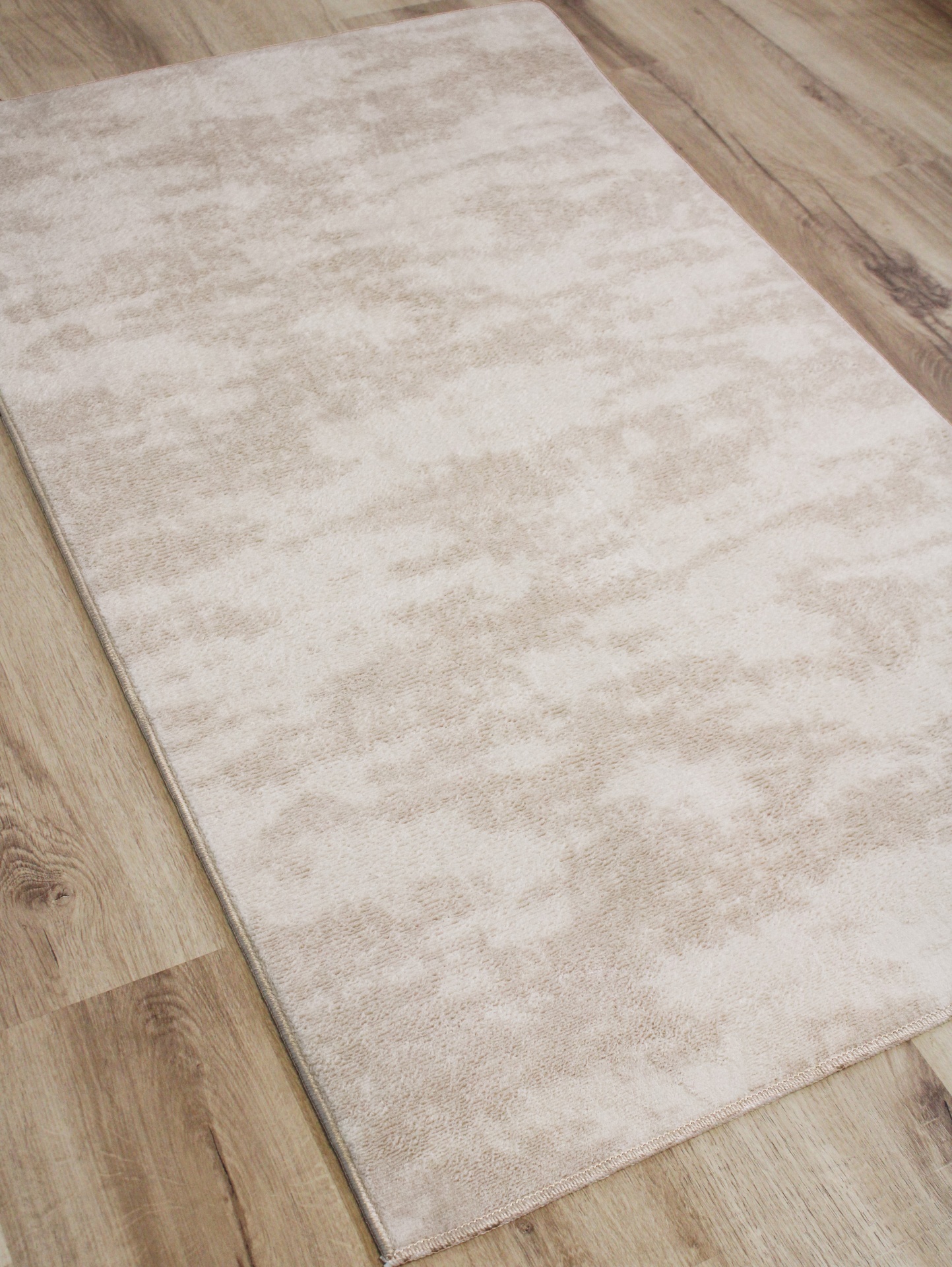 Tapete bege claro com padrão marmoreado em piso de madeira