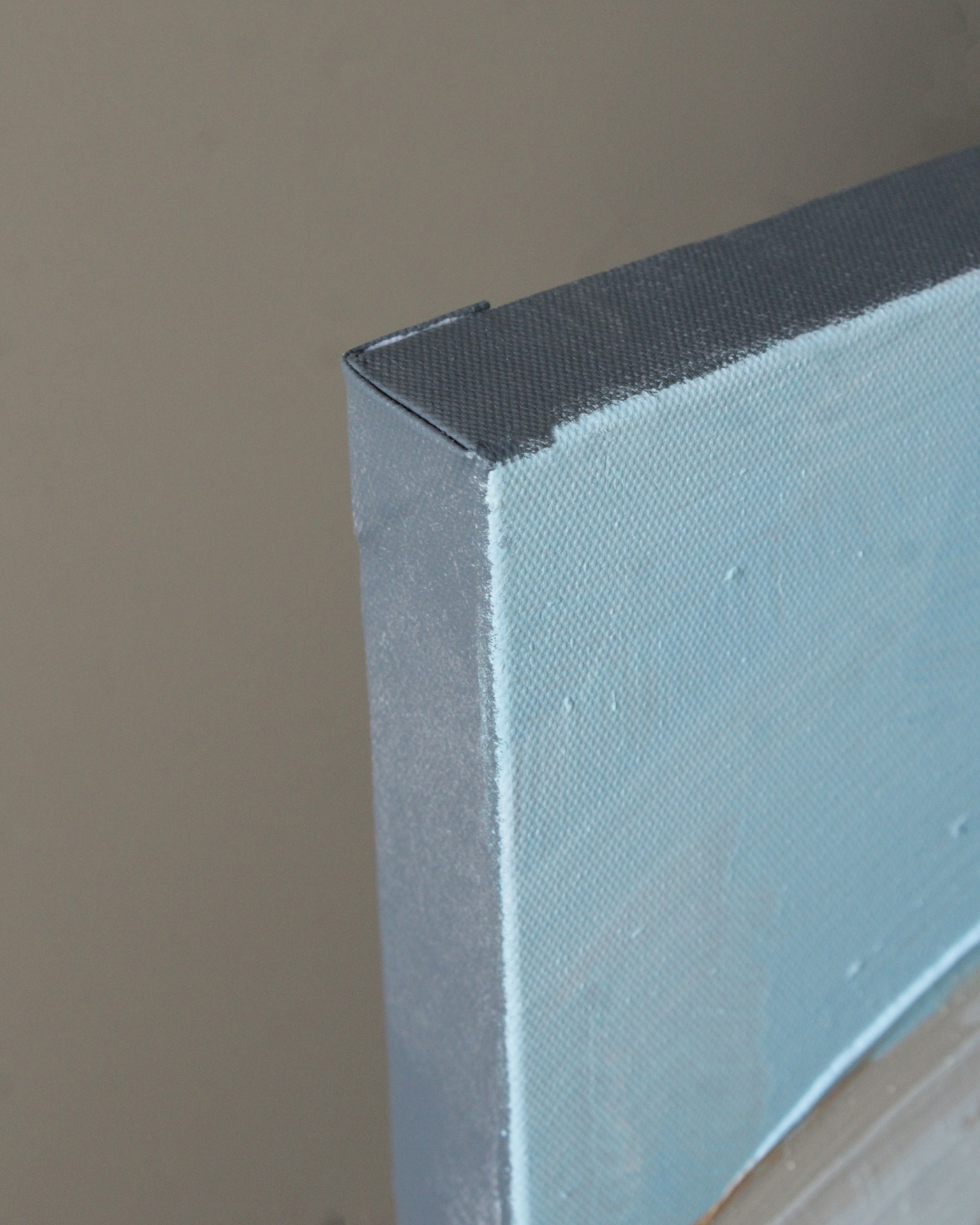 Tela esticada sobre armação de madeira com tecido azul claro e moldura preta