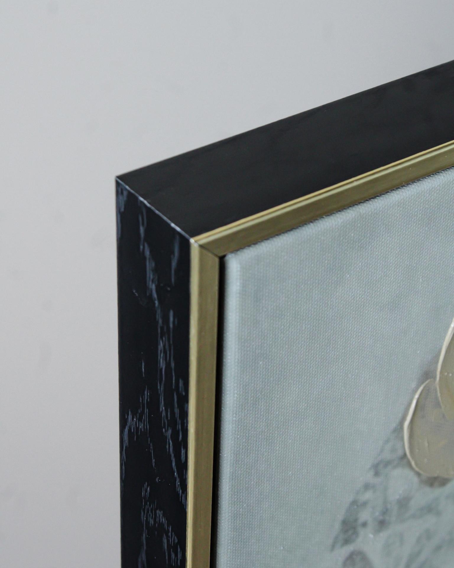 Canto de moldura preta com detalhe dourado e parte de tela pintada