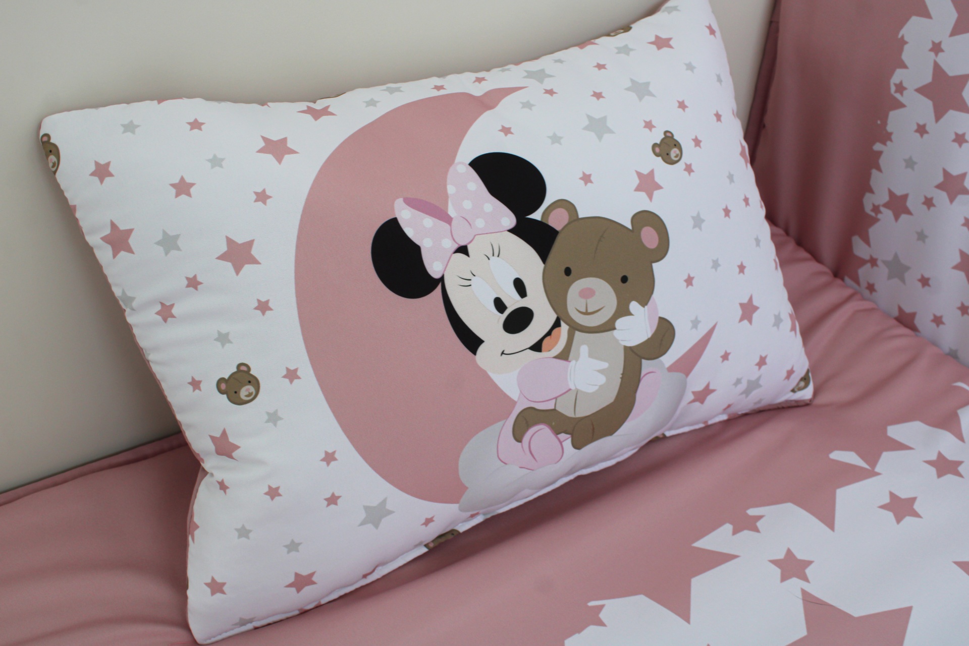 Travesseiro decorativo com estampa da Minnie e ursinho em fundo branco com estrelas e lençol rosa