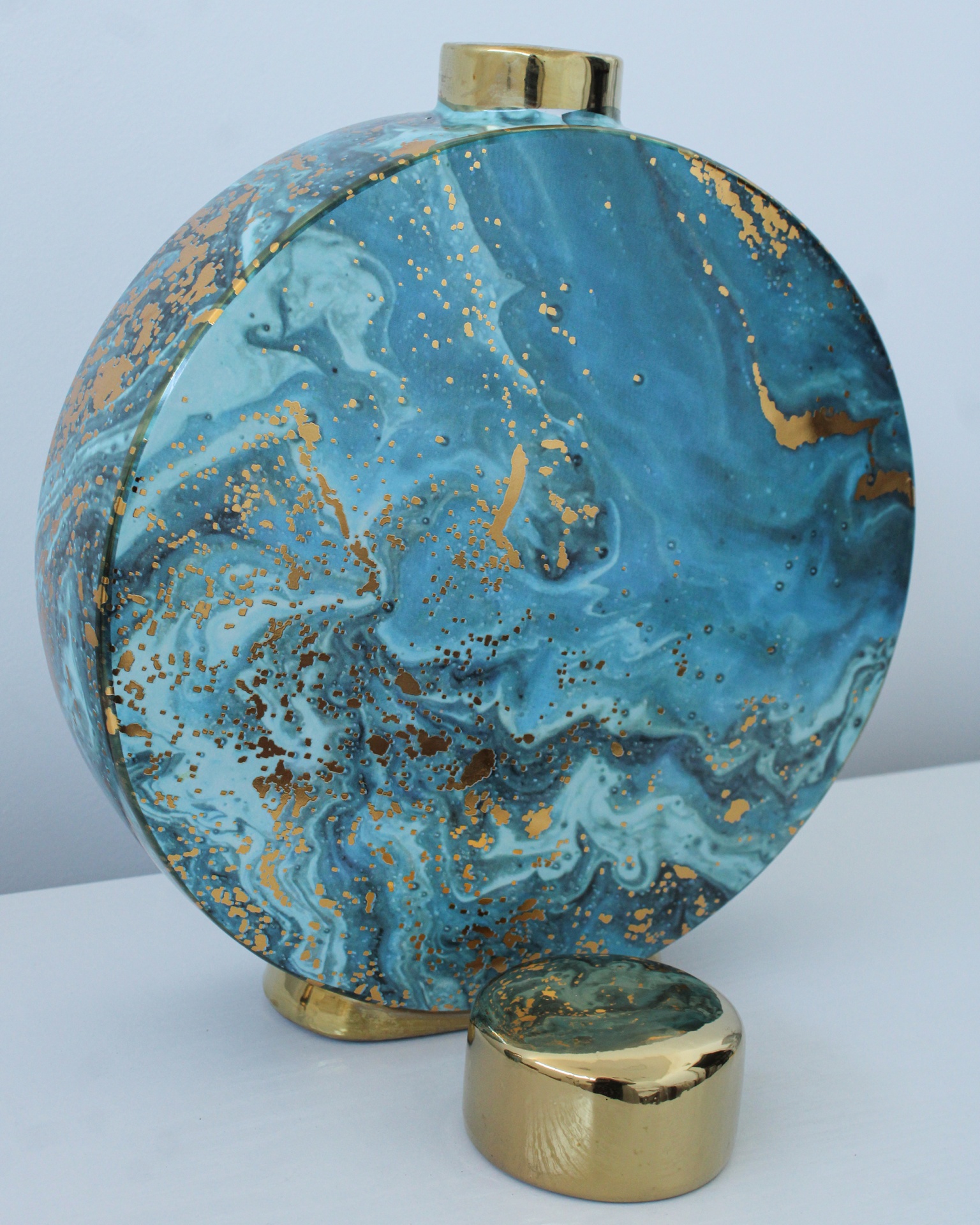 Garrafa decorativa redonda azul com detalhes dourados.