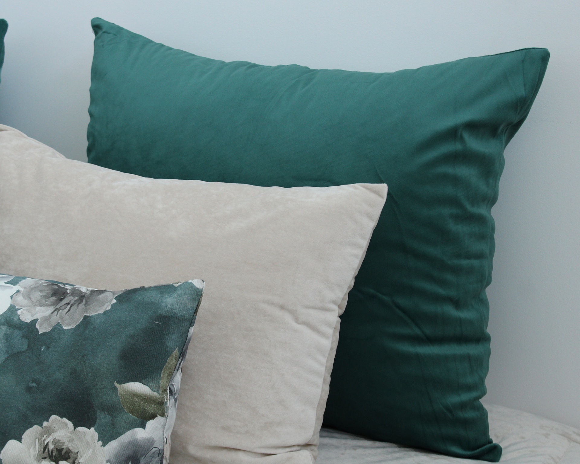 Três almofadas decorativas em cores verde, bege e com padrão floral