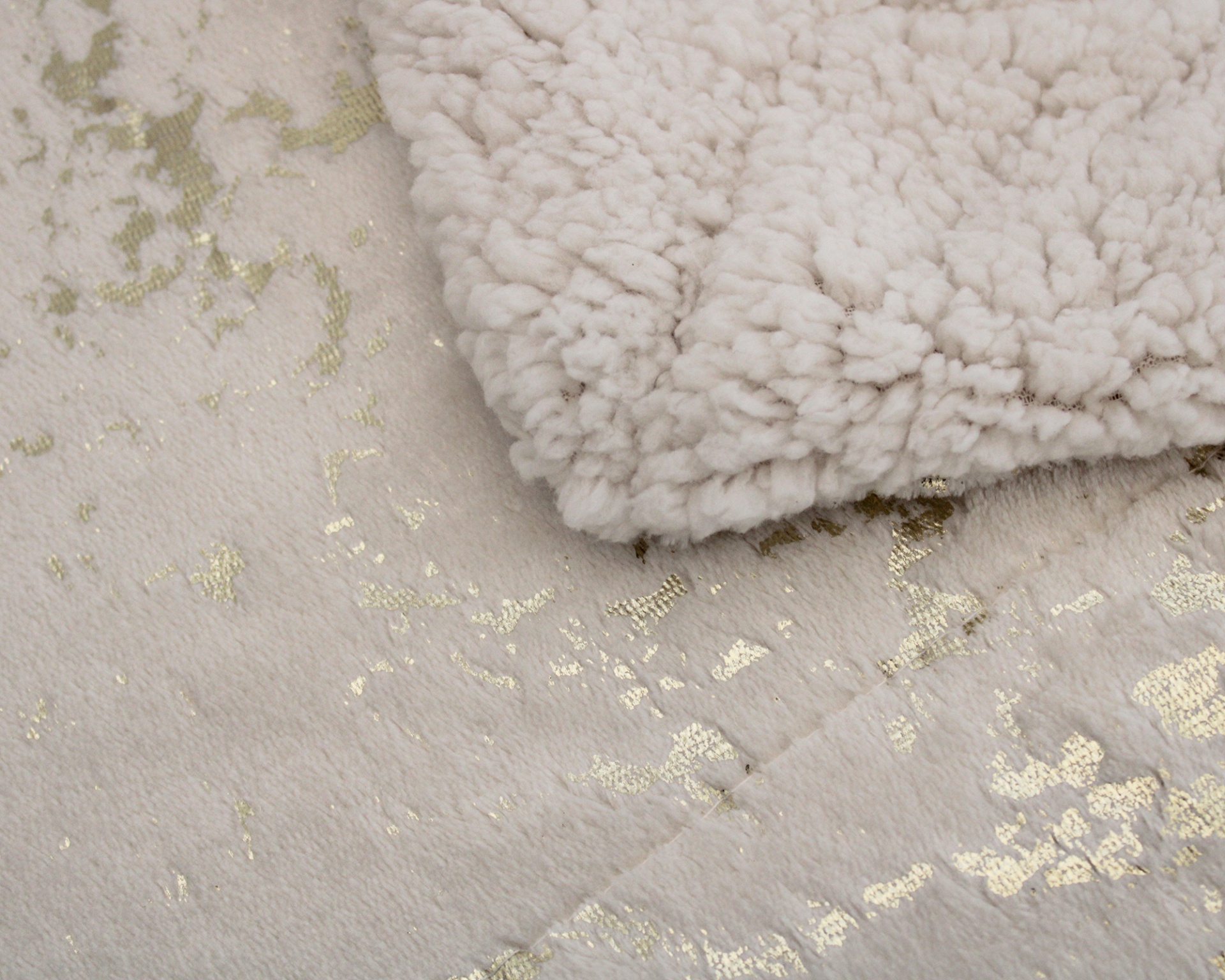 Tapete branco com padrão dourado e manta felpuda branca