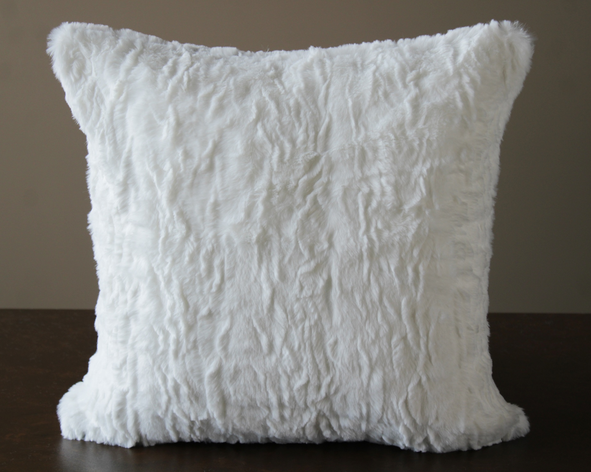 almofada branca peluda sobre superfície escura