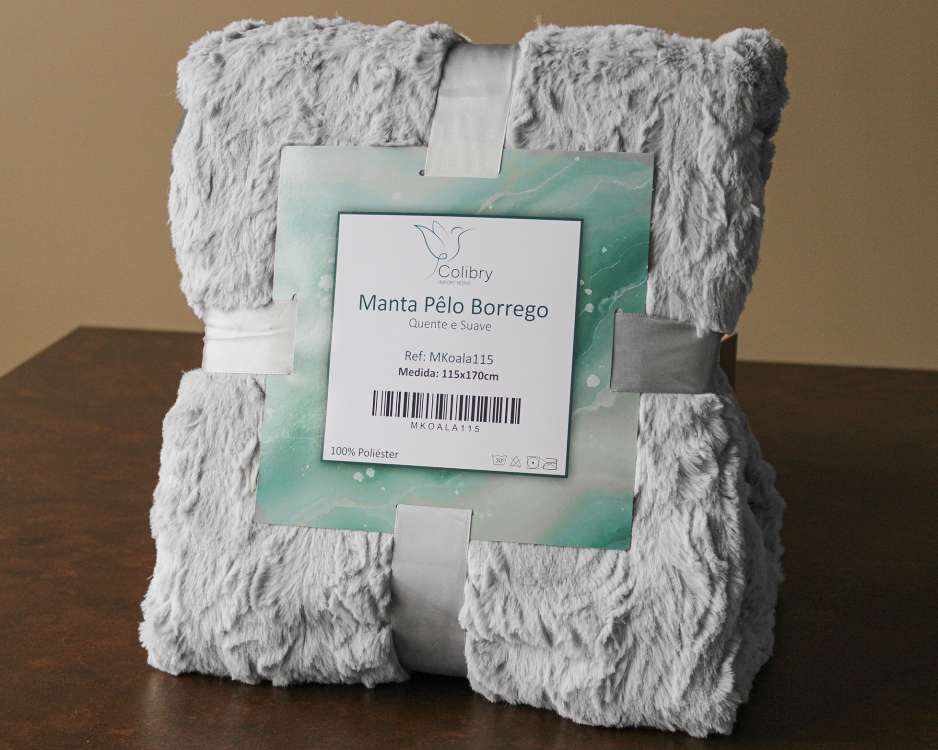 Manta cinzenta de pelo borrego dobrada com etiqueta da marca Colbtry