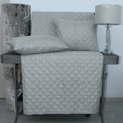 Conjunto de têxteis cinzentos acolchoados sobre móvel metálico com candeeiro e rolo de tecido