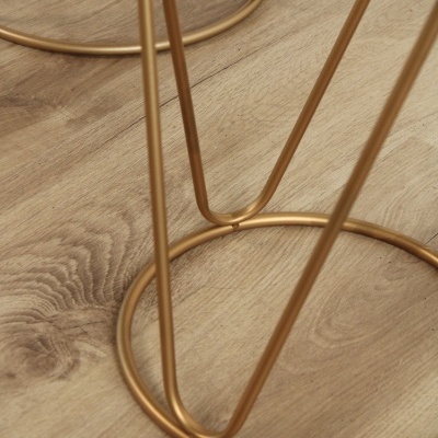 Estrutura metálica dourada tubular circular sobre chão de madeira clara