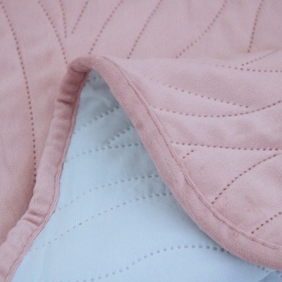 Colcha rosa claro com padrão de costura e reverso branco