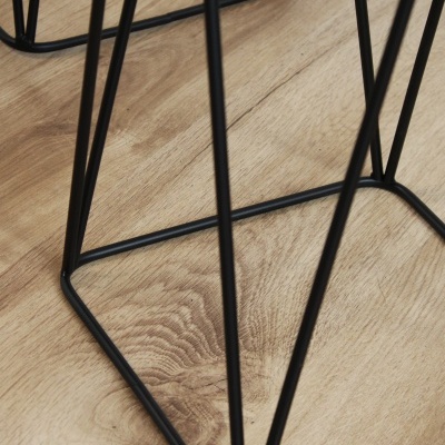 Base metálica preta com design geométrico sobre chão de madeira clara