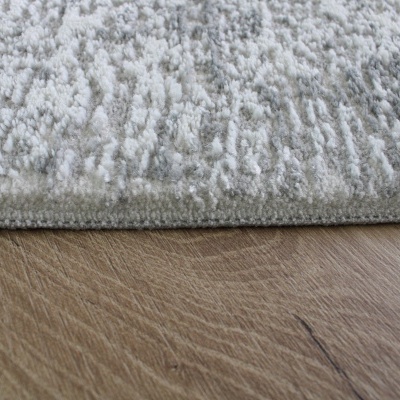 Tapete cinza claro com textura felpuda sobre chão de madeira clara