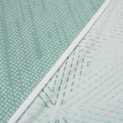 Dois tecidos com padrões distintos, um verde com pontos brancos e outro branco com linhas verdes.