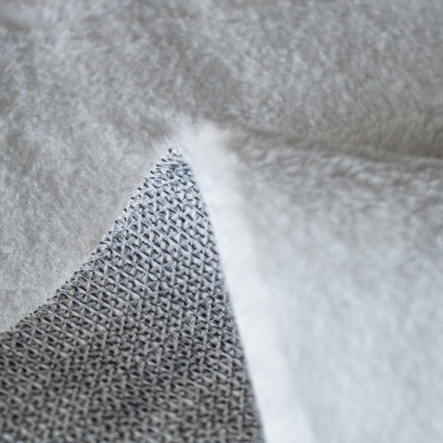 Tecido cinza com padrão entrelaçado e acabamento felpudo branco