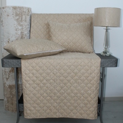 Tapete e almofadas bege acolchoadas com padrão de losangos sobre mesa preta com lâmpada