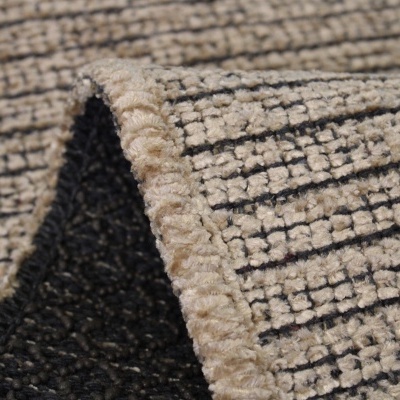 Tapete tecido bege e preto com padrão de linhas e bordas costuradas.