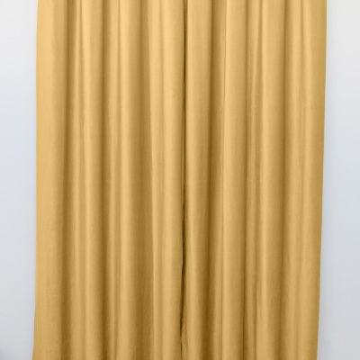 Cortina amarelo mostarda com ilhóses prateados pendurada