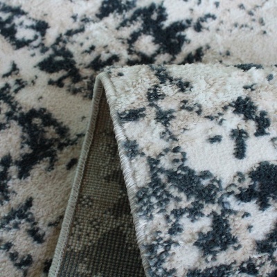 Tapete felpudo padrão abstracto bege e preto com dobra mostrando verso