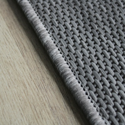 Tapete cinzento tecido sobre chão de madeira clara