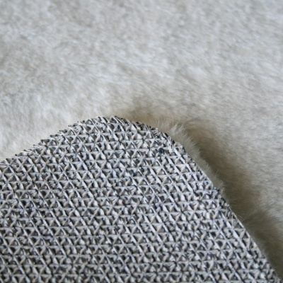 Tapete cinzento texturizado sobre superfície peluda clara