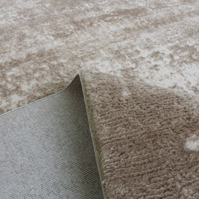 Tapete bege de tecido felpudo dobrado mostrando o verso cinza.