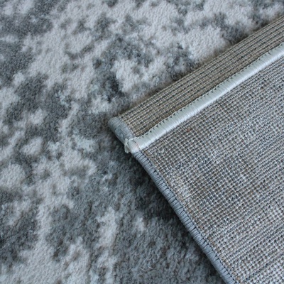 Tapete cinzento com padrão irregular e acabamento costurado