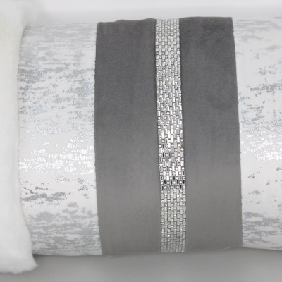 Almofada decorativa cinza e branca com faixa brilhante central e bordas felpudas