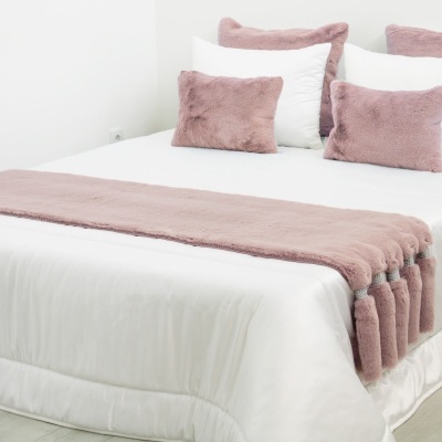 Cama branca com mantas e almofadas rosa peludas