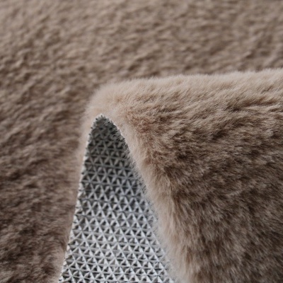 Tapete felpudo castanho claro com base antiderrapante cinzenta.