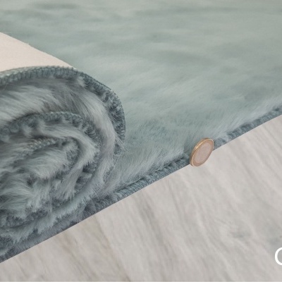 Tapete azul turquesa com textura felpuda e botão de madeira sobre piso claro.