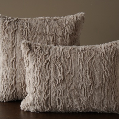 Duas almofadas decorativas de pelúcia bege claro com textura felpuda.