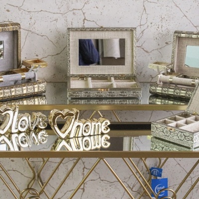 caixas organizadoras decorativas com espelho interior e objetos dourados com texto em mesa de vidro