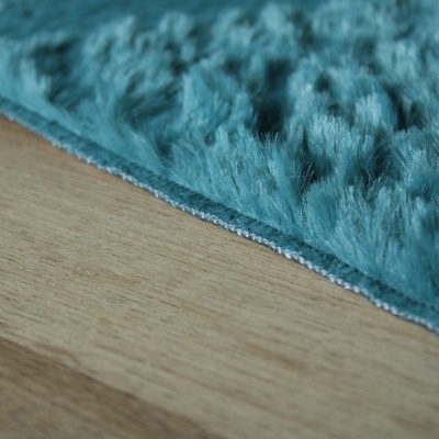 Tapete peludo azul turquesa sobre chão de madeira clara
