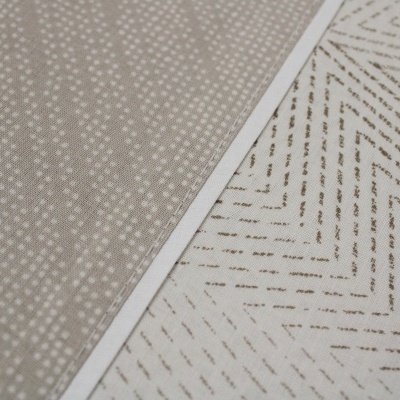 Dois tecidos sobrepostos com padrões distintos, bege com pontos brancos e branco com linhas diagonais castanhas.