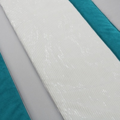 Colchão branco texturizado sobre base azul e superfície cinza