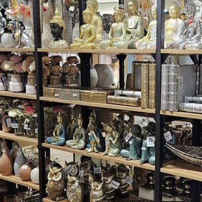 Estantes com esculturas decorativas de Buda, corujas e caixas em dourado e prateado