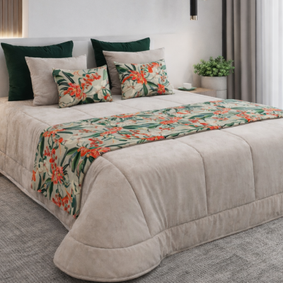 Cama com edredão bege, almofadas florais e verdes, tapete cinza e mesa de cabeceira com planta.