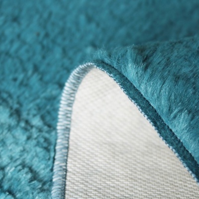 Tapete azul turquesa felpudo com borda costurada e verso branco quadriculado