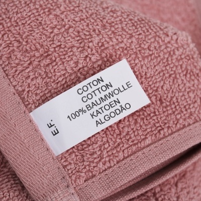 Toalha rosa de algodão com etiqueta indicando 100% algodão