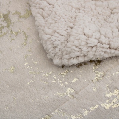 Tapete branco com padrão dourado e manta felpuda branca