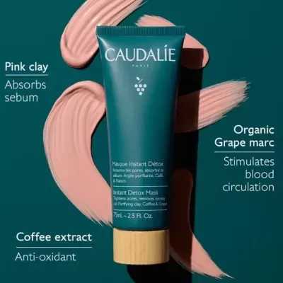 Tubo de máscara facial Caudalie Paris com tampa de madeira e manchas de argila rosa sobre fundo verde-escuro