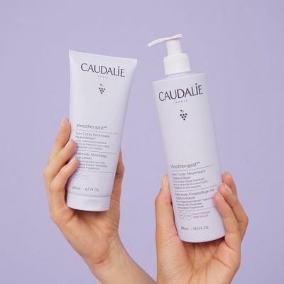 Duas embalagens de produtos Caudalie branco com texto preto sobre fundo lilás