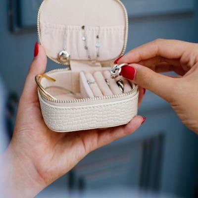 Estojo branco croco com joias em fundo azul desfocado