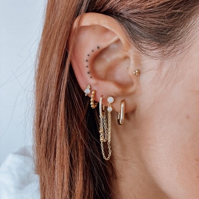 Orelha com vários brincos dourados e correntes