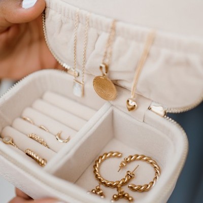 Estojo de joias bege com colares e brincos dourados variados