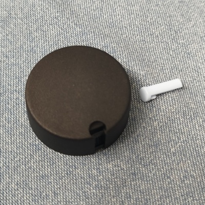 Estojo de recarga preto circular com auricular branco em tecido cinzento