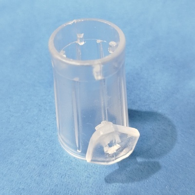 Peça pequena de plástico transparente com aba articulada sobre tecido azul