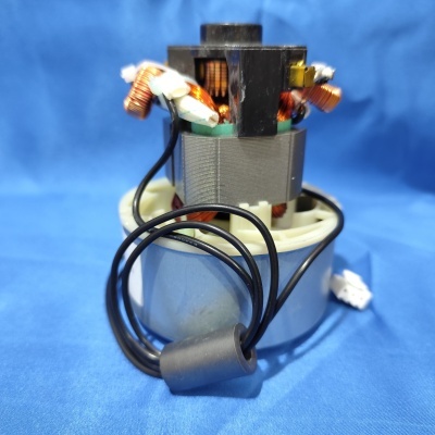 Peça eletrónica com bobinas de cobre, suportes plástico, fios pretos e pano azul