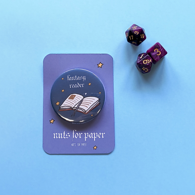 Botão redondo com livro aberto e texto fantasy reader junto a dados poliédricos roxos e cartão lilás